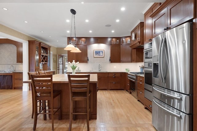 kitchen with a center island, crown molding, glass insert cabinets, light wood-type flooring, and stainless steel appliances