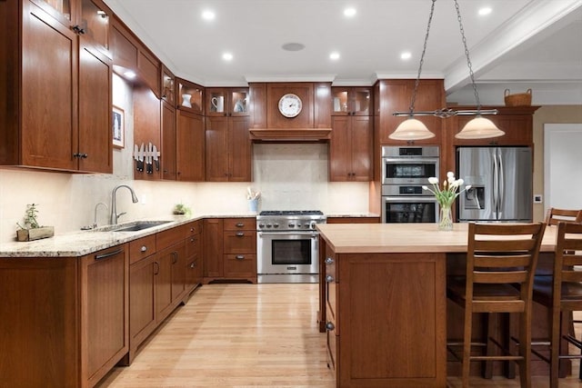 kitchen featuring a sink, decorative backsplash, light wood-style floors, and appliances with stainless steel finishes