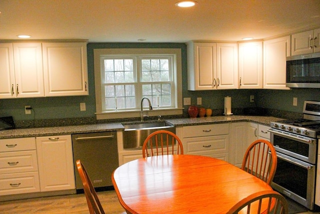 kitchen featuring white cabinetry, sink, light hardwood / wood-style flooring, and appliances with stainless steel finishes