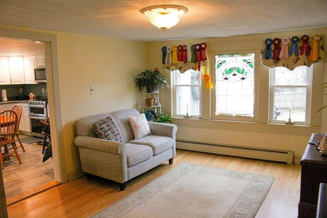 sitting room with light hardwood / wood-style flooring and a baseboard heating unit