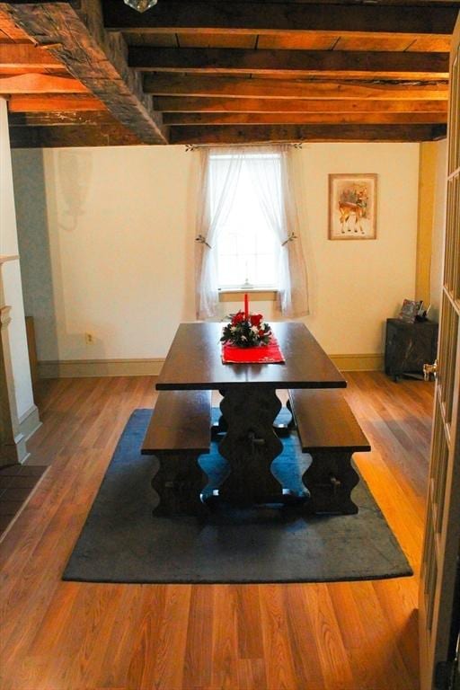 dining space with beamed ceiling and hardwood / wood-style flooring