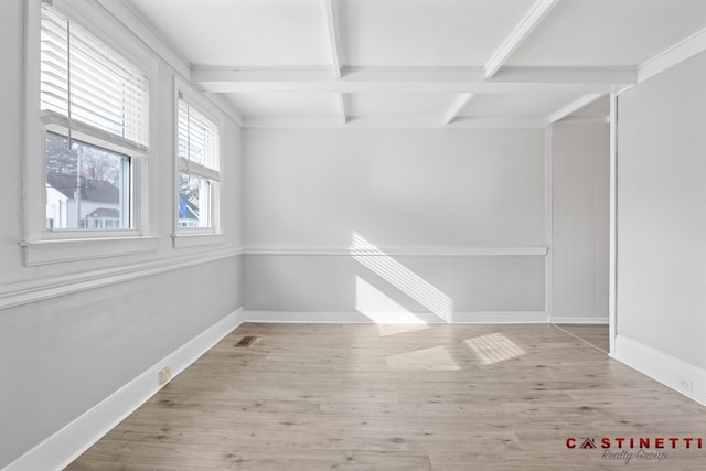 unfurnished room with beamed ceiling and light wood-type flooring