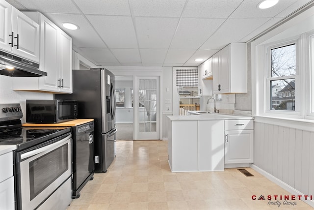 kitchen with sink, a paneled ceiling, black appliances, decorative backsplash, and white cabinets