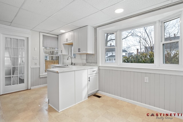 kitchen featuring white cabinetry, sink, a drop ceiling, and kitchen peninsula