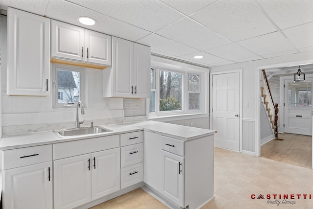 kitchen featuring white cabinetry, a drop ceiling, sink, and a wealth of natural light