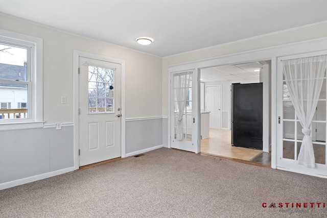 foyer with crown molding and carpet flooring