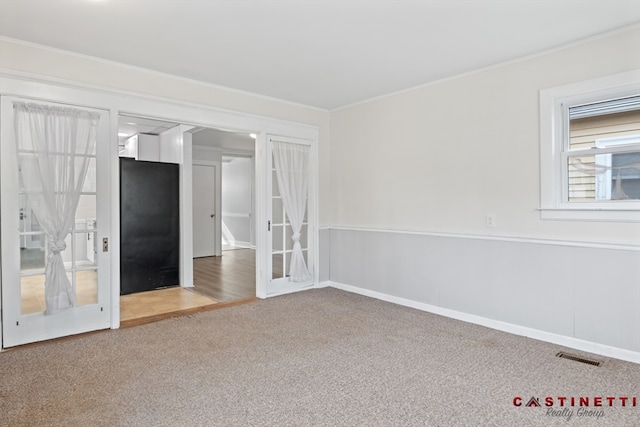 empty room with crown molding, carpet flooring, and french doors