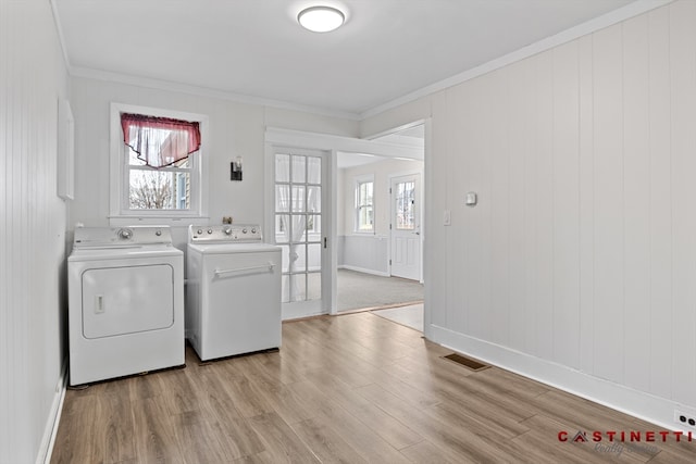 laundry area featuring crown molding, washing machine and dryer, and light hardwood / wood-style floors