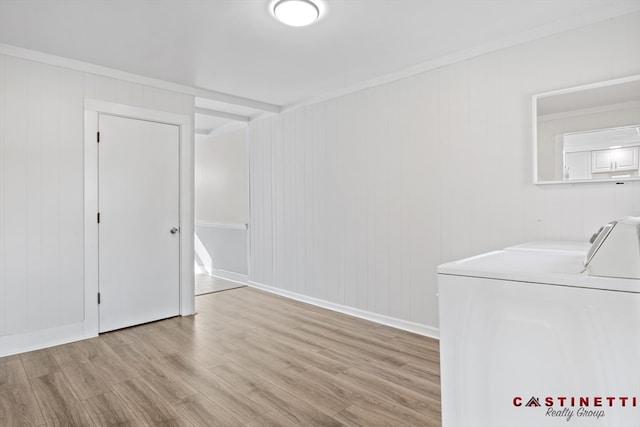 unfurnished room with crown molding, washer and clothes dryer, and light wood-type flooring