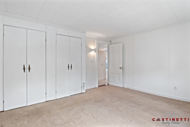 unfurnished bedroom with light carpet and two closets