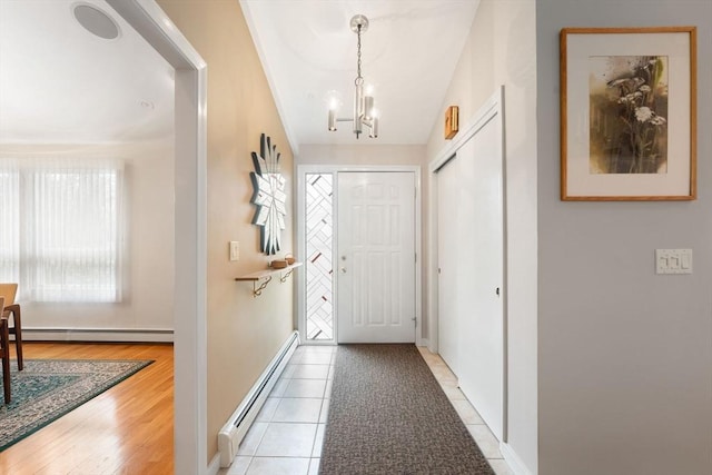 foyer featuring light tile patterned floors, a baseboard heating unit, baseboards, and a chandelier