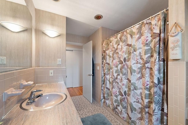 full bath featuring a shower with shower curtain, tile walls, and vanity