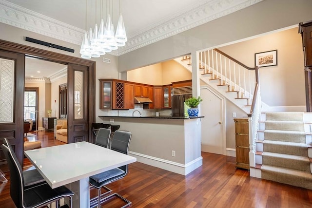 dining area with dark hardwood / wood-style flooring, crown molding, a high ceiling, and a chandelier