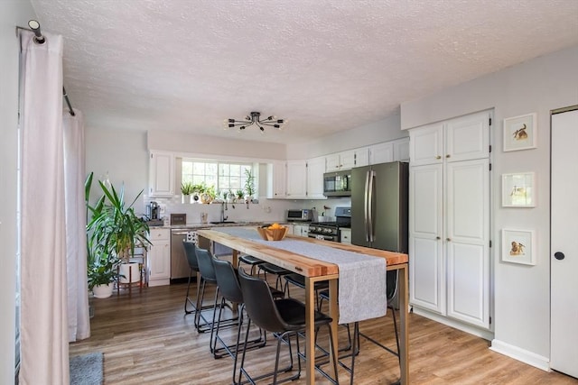 3 Treasure Way Unit 3, Ashland, MA 01721 - kitchen featuring appliances with stainless steel finishes, white cabinetry, a textured ceiling, light wood finished floors, and light countertops