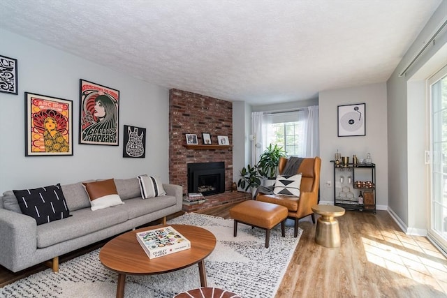 3 Treasure Way Unit 3, Ashland, MA 01721 - living area featuring wood finished floors, a brick fireplace, and a textured ceiling