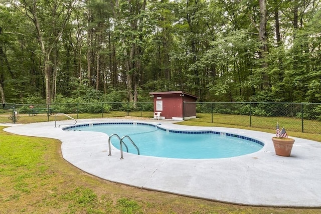 420 Great Rd Unit B9, Acton, MA 01720 - view of swimming pool featuring an outdoor structure, a storage shed, and a wooded view