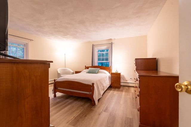 420 Great Rd Unit B9, Acton, MA 01720 - bedroom with baseboard heating, light wood-style flooring, a textured ceiling, and baseboards