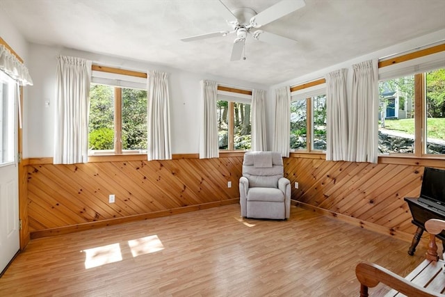 unfurnished room with wooden walls, wainscoting, a wealth of natural light, and light wood-type flooring