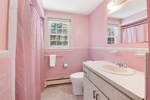 full bath with vanity, toilet, tile walls, baseboard heating, and tile patterned floors