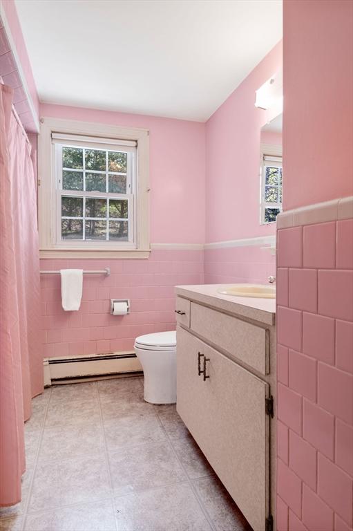 full bathroom with vanity, wainscoting, toilet, tile walls, and baseboard heating