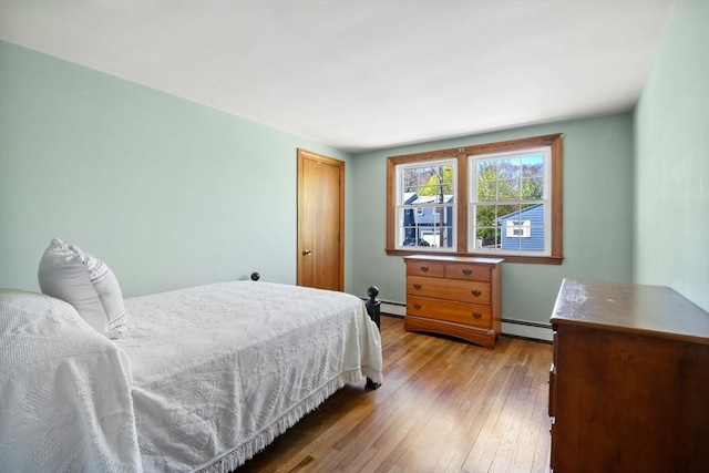 bedroom featuring a baseboard heating unit, a baseboard radiator, hardwood / wood-style flooring, and a closet