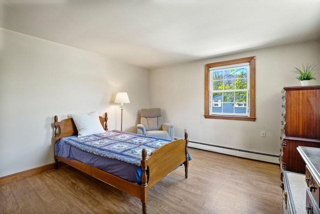 bedroom with light wood-style floors, baseboards, and a baseboard heating unit