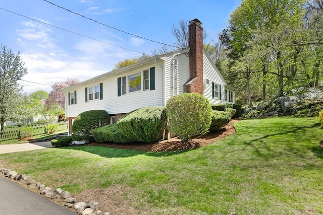 view of property exterior with a lawn, fence, and a chimney