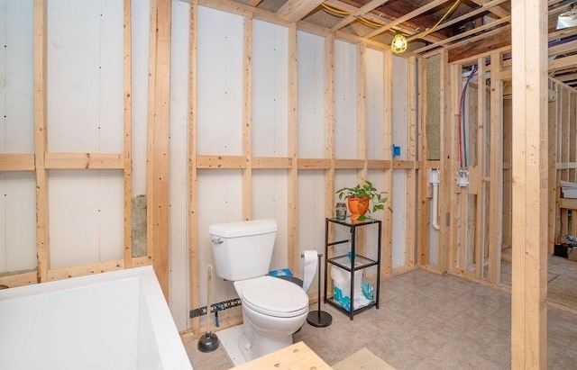 bathroom featuring tile patterned floors, toilet, and a tub to relax in