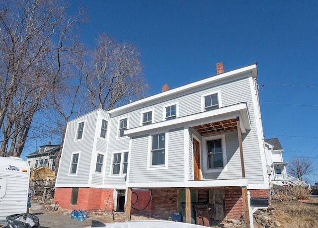 rear view of property featuring brick siding and a chimney