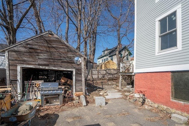 view of patio featuring a garage, a grill, an outdoor structure, and fence