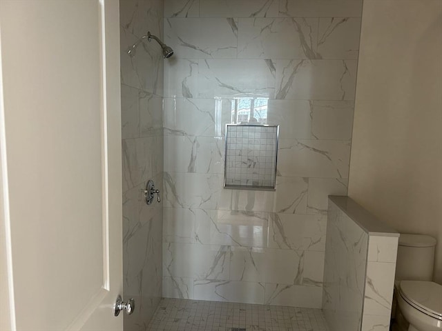 bathroom featuring tiled shower and toilet