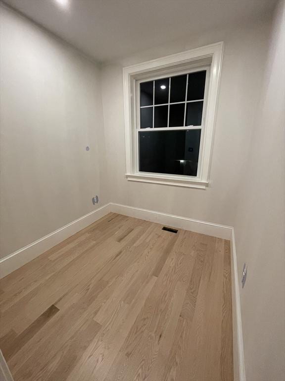 unfurnished room featuring light wood-style flooring, visible vents, and baseboards