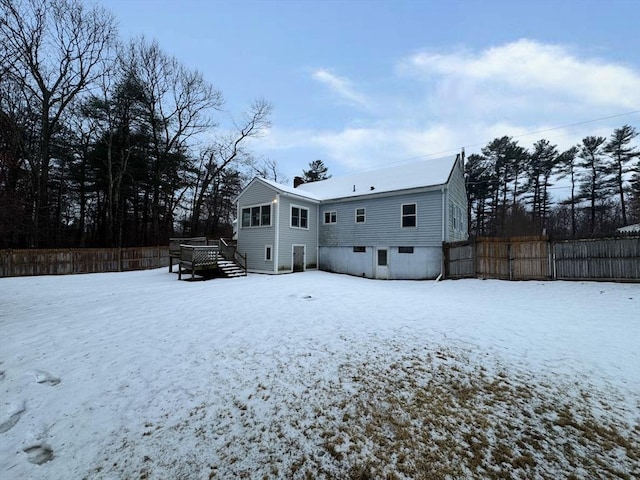 snow covered back of property featuring fence and a wooden deck