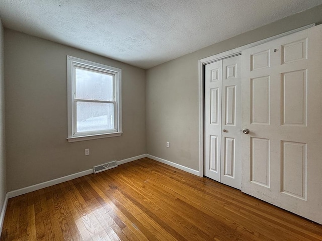 2248 Washington St, East Bridgewater, MA 02333 - unfurnished bedroom with visible vents, a textured ceiling, baseboards, and wood finished floors