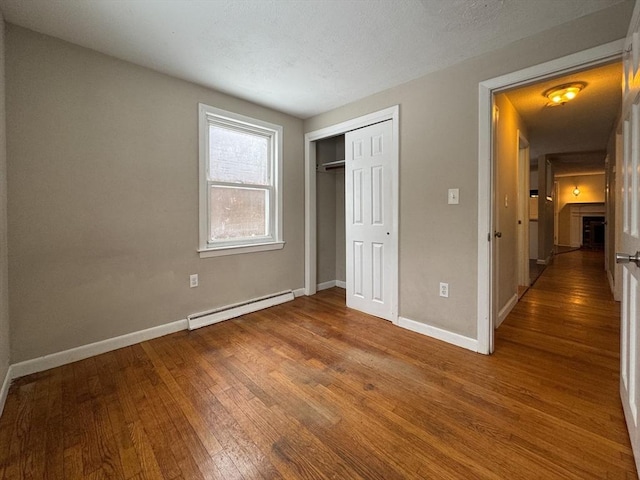 2248 Washington St, East Bridgewater, MA 02333 - unfurnished bedroom with a fireplace, wood-type flooring, a closet, a baseboard heating unit, and baseboards