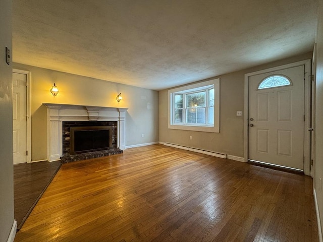 2248 Washington St, East Bridgewater, MA 02333 - unfurnished living room with hardwood / wood-style flooring, a baseboard radiator, a brick fireplace, and baseboards