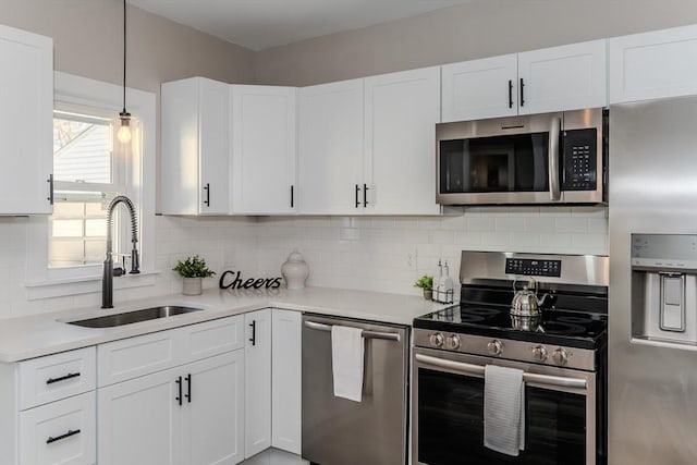 kitchen with appliances with stainless steel finishes, light countertops, a sink, and decorative backsplash