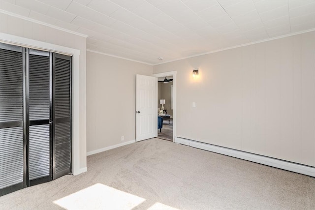 unfurnished bedroom featuring a closet, baseboard heating, ornamental molding, carpet flooring, and baseboards