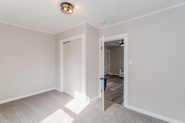 unfurnished bedroom with a baseboard radiator, carpet floors, baseboards, ornamental molding, and a closet