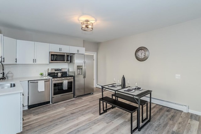 kitchen with appliances with stainless steel finishes, light countertops, light wood-style floors, and white cabinetry