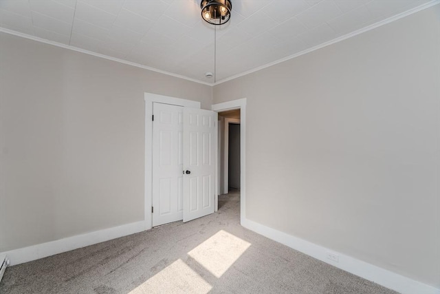 carpeted empty room featuring baseboard heating, crown molding, and baseboards