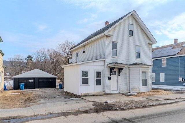 view of front of home with a garage, a chimney, and an outbuilding