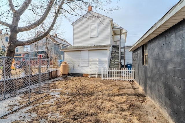 rear view of property featuring fence and stairway