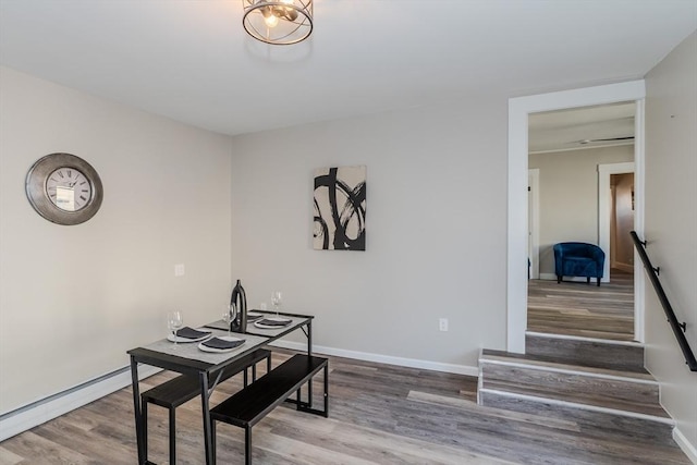 dining room with a baseboard radiator, stairway, baseboards, and wood finished floors