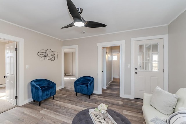 interior space featuring baseboards, ornamental molding, ceiling fan, and wood finished floors