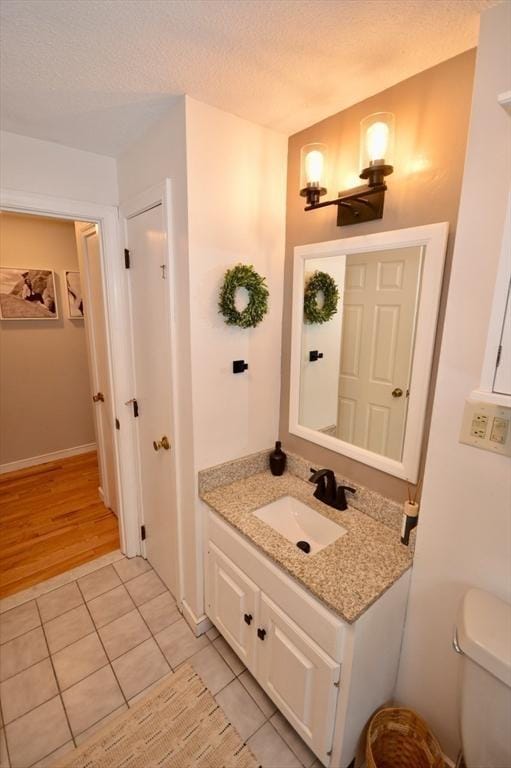 bathroom with baseboards, toilet, tile patterned flooring, a textured ceiling, and vanity