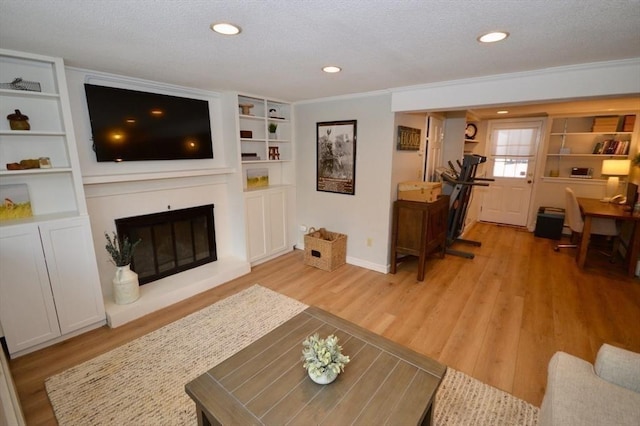 living room with a textured ceiling, a glass covered fireplace, light wood-style flooring, and baseboards