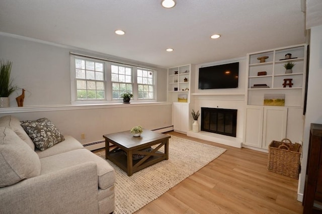 living area featuring a glass covered fireplace, a baseboard radiator, light wood-style flooring, and recessed lighting