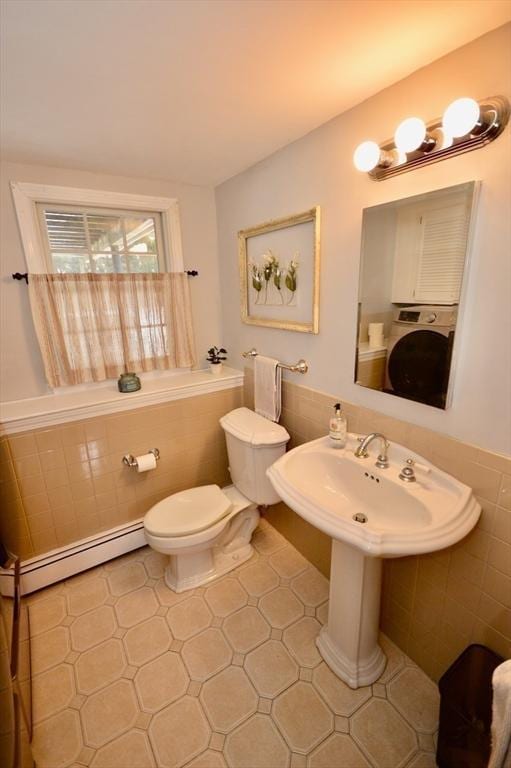 half bath with washer / clothes dryer, toilet, tile walls, and baseboard heating