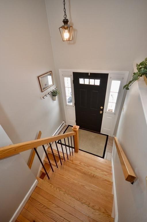 foyer with stairs, a healthy amount of sunlight, a towering ceiling, and light wood-style floors